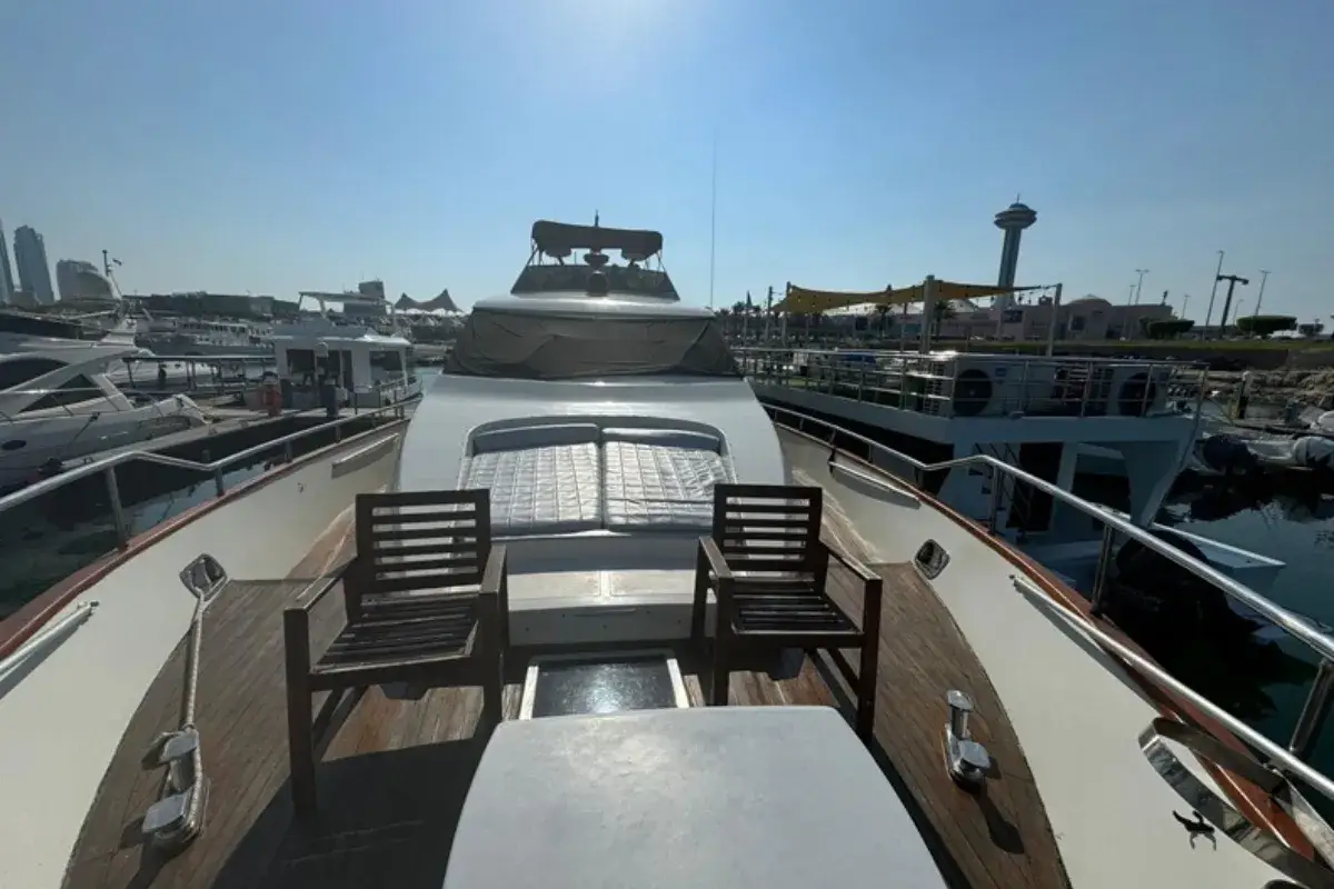 Foredeck of the 62 Ft Tecno Yacht with a sunpad and two wooden chairs, moored at a marina in Abu Dhabi
